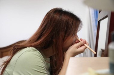 Güneydoğu Asyalı bir kadın dışarı çıkmak için makyaj yapıyor..