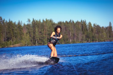 Kadın çalışma wakeboarding bir göl kenarında
