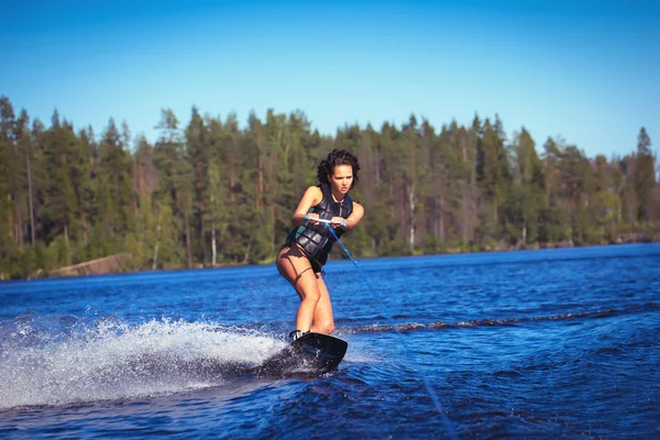 Kadın çalışma wakeboarding bir göl kenarında