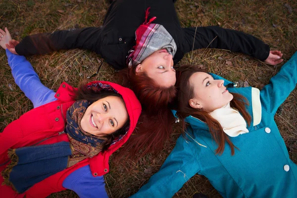 Tre giovane donna sdraiata su un'erba di autunno — Foto Stock