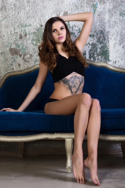 Hermosa joven bonita mujer morena con tatuaje en el sofá —  Fotos de Stock