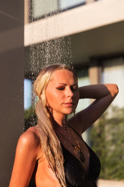 Slim blonde woman taking shower near pool outdoors — Stockfoto