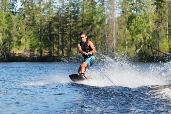 Giovane uomo a cavallo wakeboard sul lago estivo — Foto Stock