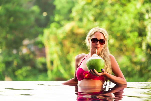 Unga vackra blonda kvinnan i poolen kokos cocktail — Stockfoto