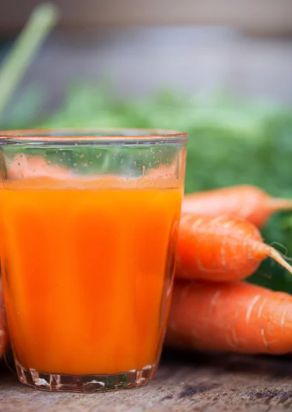 Morotsjuice på trä bakgrund — Stockfoto