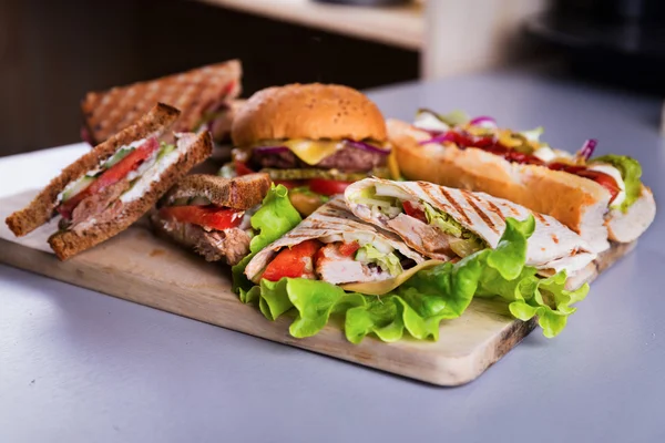 Rychlé občerstvení deska s hamburger párek sendviče kuře zábal — Stock fotografie