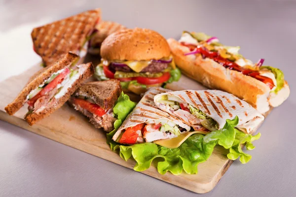 Placa de comida rápida con sándwiches de hamburguesa hot dog pollo envoltura — Foto de Stock