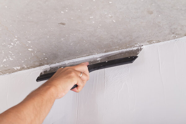 house improvement worker puts finishing layer of stucco on wall