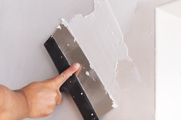 house improvement worker puts finishing layer of stucco on wall