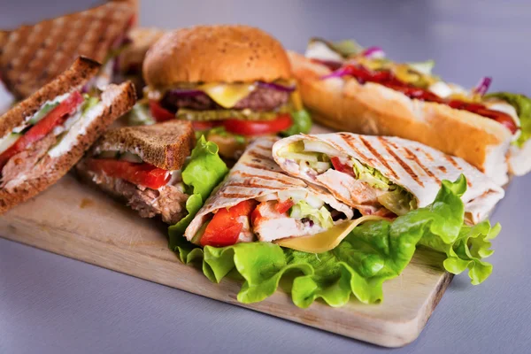 Rychlé občerstvení deska s hamburger párek sendviče kuře zábal — Stock fotografie