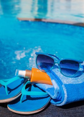 Mavi terlik, sunsscreen krem ve güneş gözlüğü yakın Yüzme po