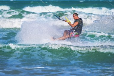 Atletik adam uçurtma sörf tahtası üzerinde deniz dalgaları sürme