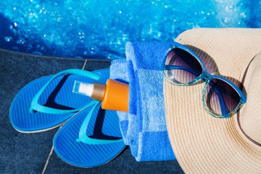 terlik, sunsscreen krem, şapka, güneş gözlüğü yakın Yüzme Havuzu tatil kavramı