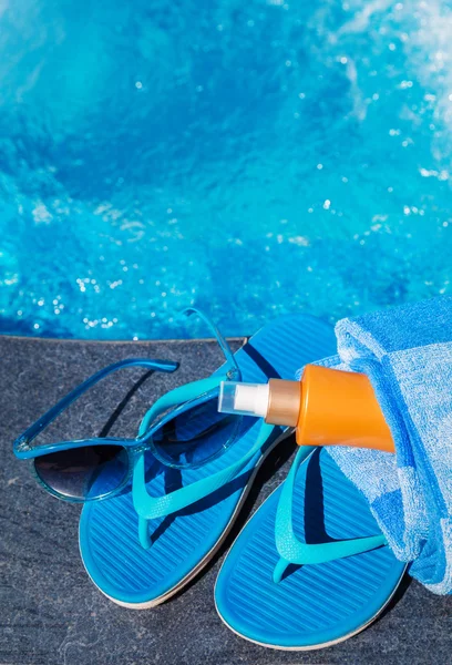 Blaue Hausschuhe, Sonnencreme und Sonnenbrille in Schwimmbadnähe — Stockfoto