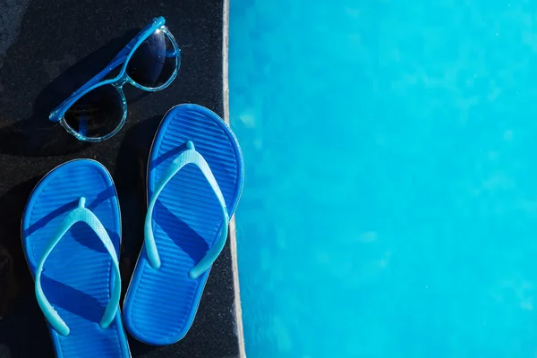 Blaue Hausschuhe und Sonnenbrille beim Schwimmbad-Urlaubskonzept — Stockfoto