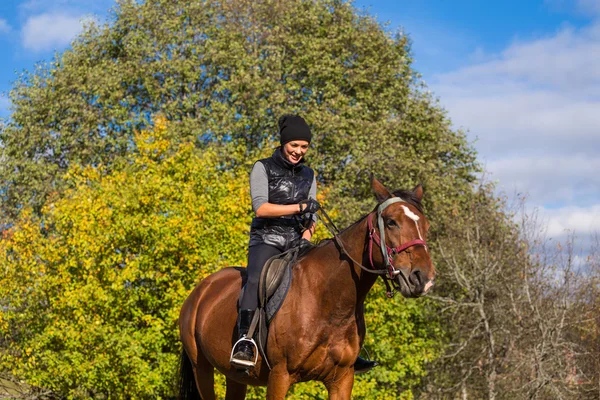 Elegante attraktive Frau reitet auf einer Pferdewiese — Stockfoto