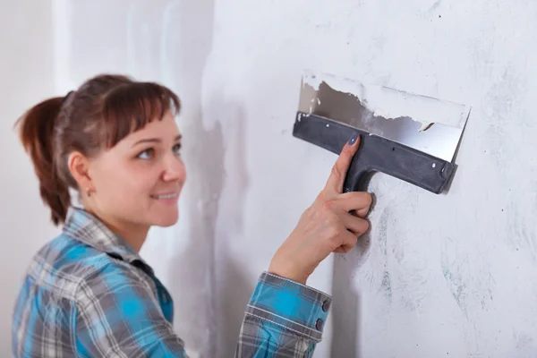 house improvement. woman worker puts stucco on wall