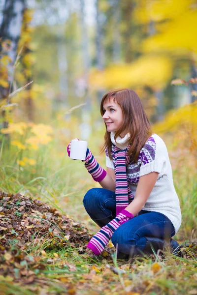 Mooie vrouw met thee kopje in herfst park — Stockfoto