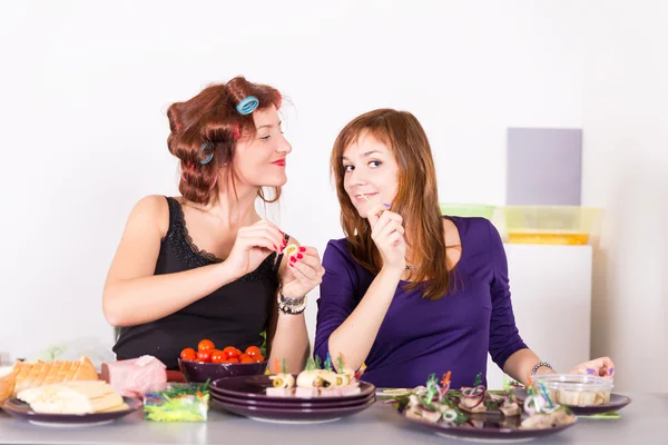 Two young pretty woman housewife cooking with curlers hair Stock Image