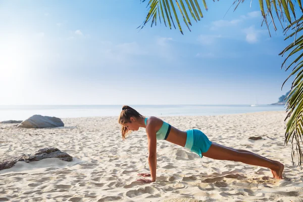 Jeune jolie femme brune mince pratique la pose de yoga sur tropical — Photo
