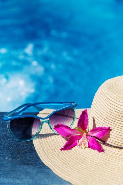Bir Yüzme Havuzu üzerine çiçek ve hasır şapka ile güneş gözlüğü