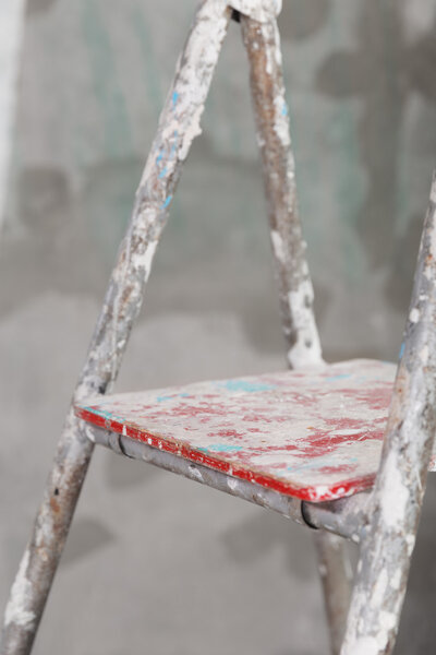 Old painted and stucco ladder on concrete wall background