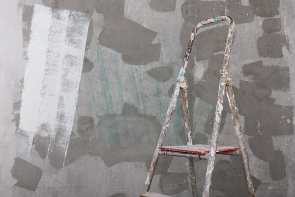 Old painted and stucco ladder on concrete wall background