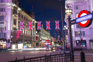 United Kingdom, England, London - 2016 June 17: Popular tourist Picadilly circus with flags union jack in night lights illumination clipart