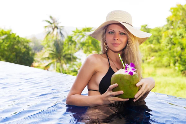 Young slim blonde woman hat drinks healthy coconut juice — Stock Photo, Image