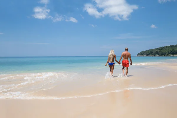 Bella coppia che si tiene per mano camminando sulla spiaggia tropicale estiva — Foto Stock