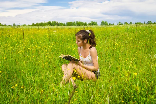 Jeune femme lecture livre sur prairie — Photo