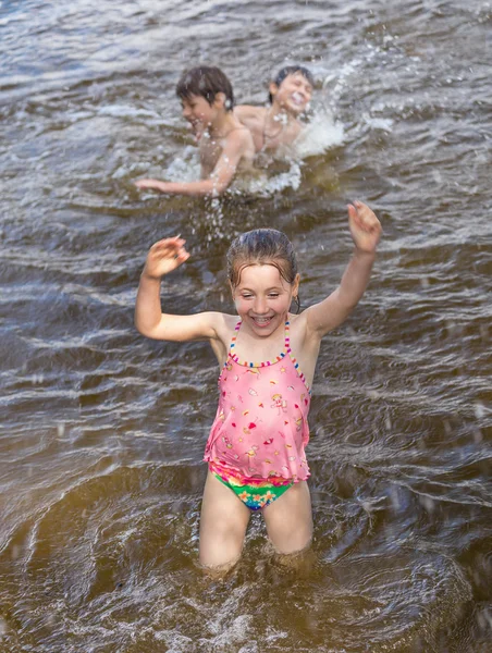 Liten flicka och hennes bröder spelar i en sjö — Stockfoto