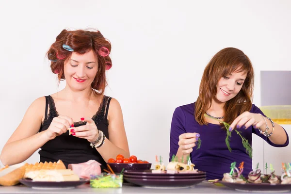 Zwei junge hübsche Hausfrauen kochen mit Lockenwicklern auf Haaren — Stockfoto