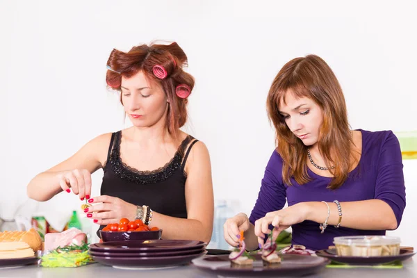 Zwei junge hübsche Hausfrauen kochen mit Lockenwicklern auf Haaren — Stockfoto