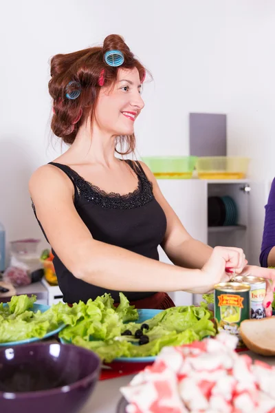 Junge hübsche Hausfrau kocht mit Lockenwicklern auf Haaren — Stockfoto