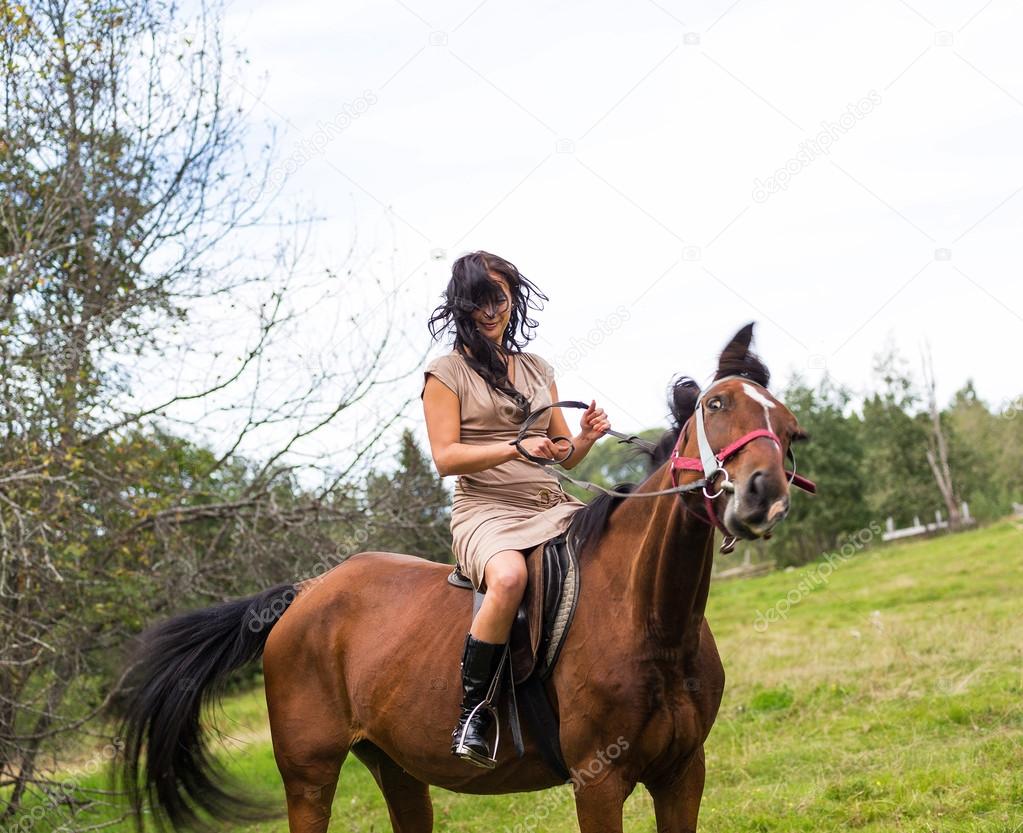 Elegant attractive woman riding a horse meadow