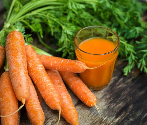 Morotsjuice på trä bakgrund — Stockfoto