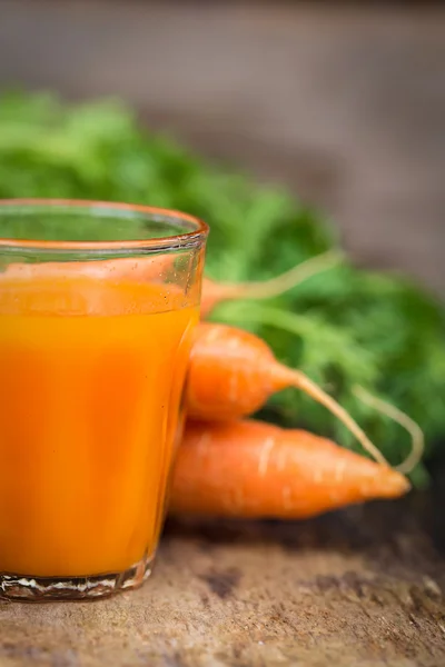 Karottensaft auf Holzgrund — Stockfoto