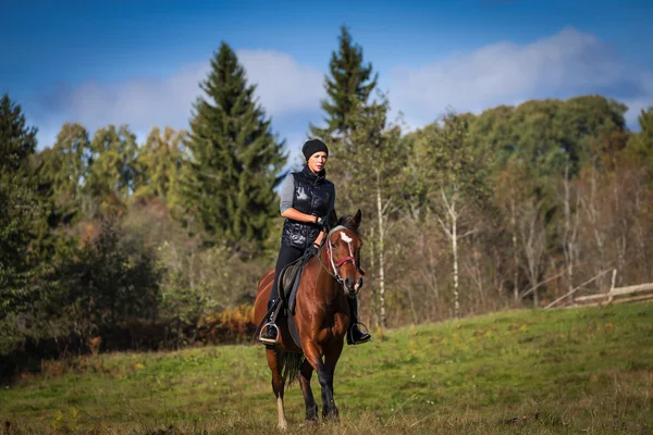 Elegante mujer atractiva montando un caballo — Foto de Stock