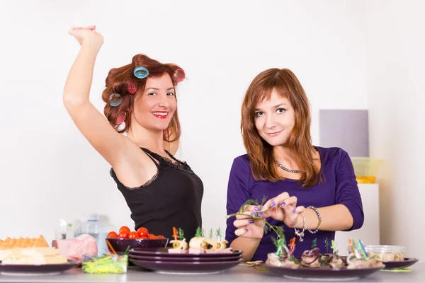 Zwei junge hübsche Hausfrauen kochen mit Lockenwicklern — Stockfoto