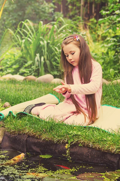 Petite fille nourrit les poissons — Photo