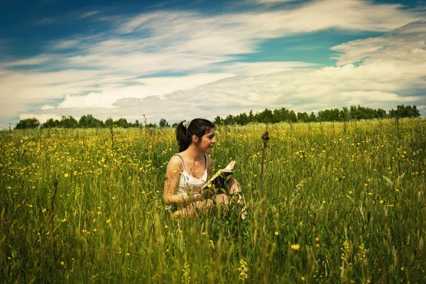 Jeune femme lisant un livre sur une prairie — Photo