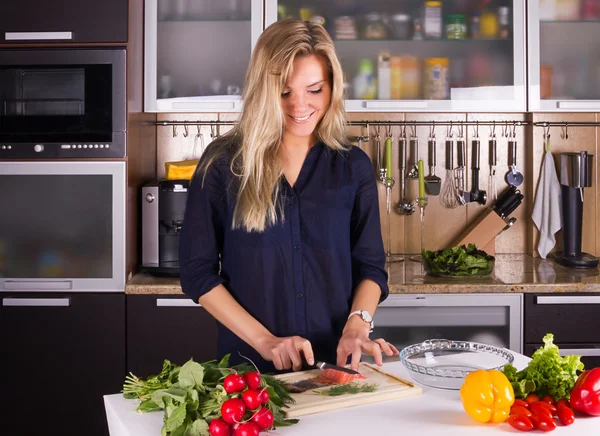 Jonge mooie jonge vrouw salade in de keuken koken — Stockfoto