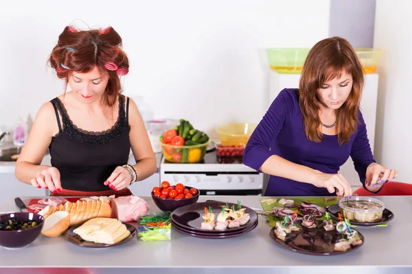 Zwei junge hübsche Hausfrauen kochen mit Lockenwicklern auf Haaren — Stockfoto