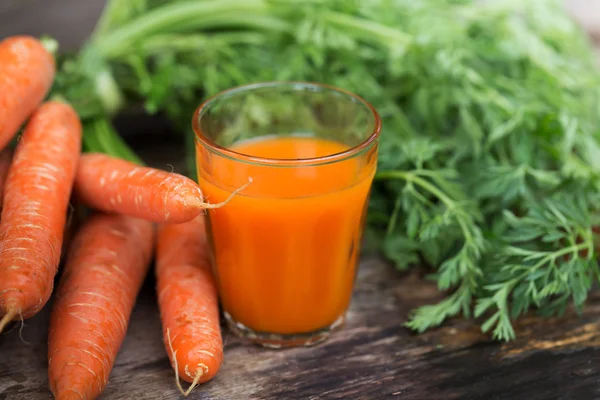 Morotsjuice på trä bakgrund — Stockfoto