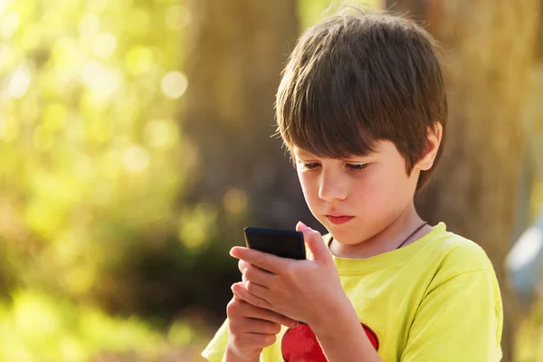 Child playing mobile phone outdoors — Stock Photo, Image