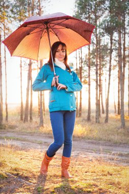 Ormanda günbatımı ışıklarda şemsiye ile genç kadın