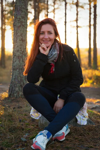 Mulher em um pôr do sol ilumina na floresta de outono — Fotografia de Stock