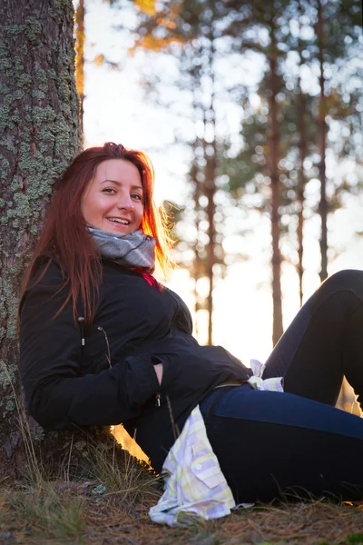 Mulher em um pôr do sol ilumina na floresta de outono — Fotografia de Stock