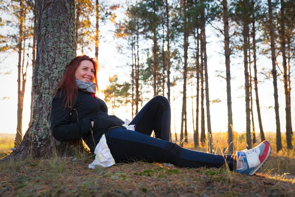 Mujer en una puesta de sol luces en el bosque de otoño — Foto de Stock